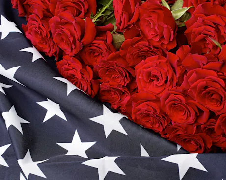 Red rose arrangement draped with American flag fabric for patriotic Fourth of July floral d&eacute;cor